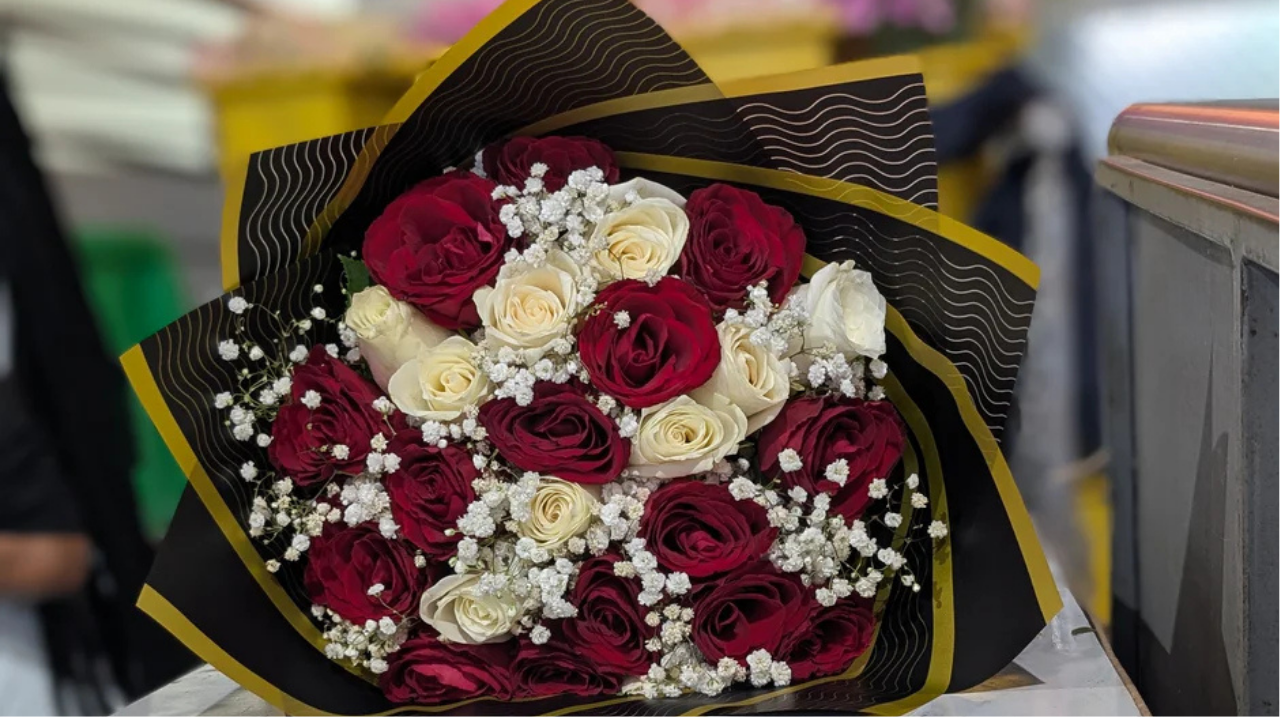 Red and white rose bouquet with baby’s breath in elegant wrap, showing flower colour meanings of love, purity, and balance