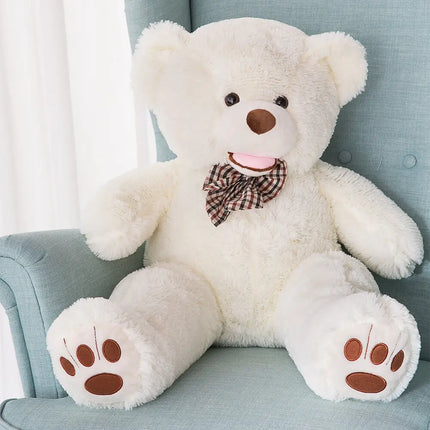 100cm big white teddy bear with soft plush fabric, bow tie, and paw details seated on chair.