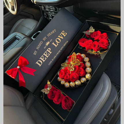 Luxury black gift box with red roses and Ferrero Rocher chocolates arranged in heart shape inside car interior