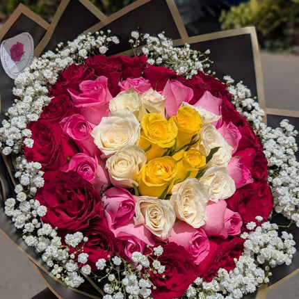 Colourful rose bouquet with red, pink, white and yellow roses surrounded by baby’s breath in elegant wrapping