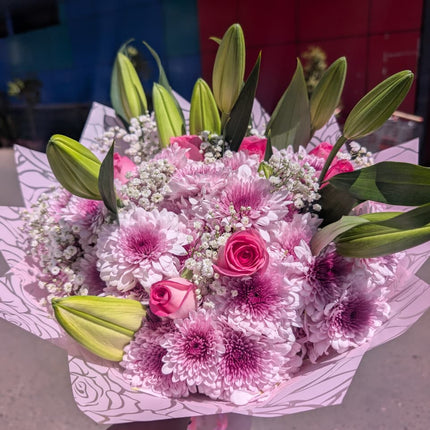 Pink bouquet with roses, chrysanthemums, lilies and baby’s breath wrapped in pastel paper for gifting