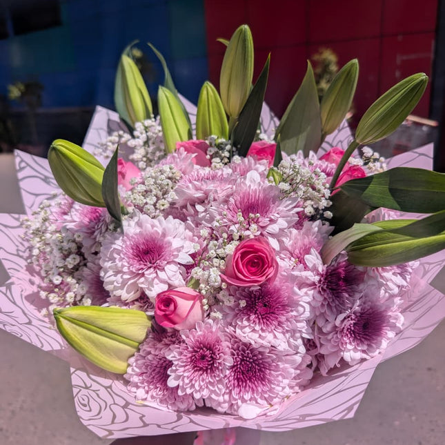 Pink bouquet with roses, chrysanthemums, lilies and baby’s breath wrapped in pastel paper for gifting