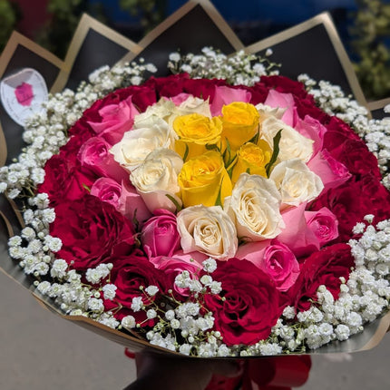 Colourful rose bouquet with red, pink, white and yellow roses surrounded by baby’s breath in elegant wrapping