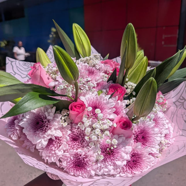 Pink bouquet with roses, chrysanthemums, lilies and baby’s breath wrapped in pastel paper for gifting