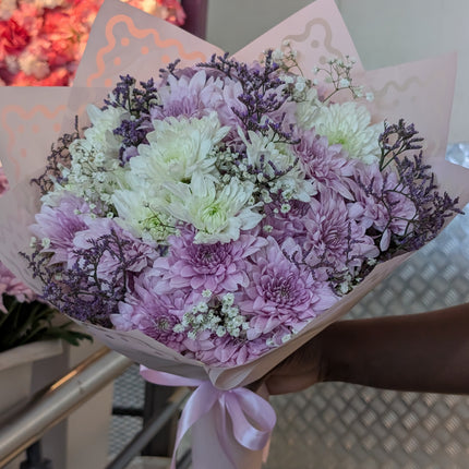 Soft Serenity flower bouquet with soft pink and white chrysanthemums wrapped in pastel paper and ribbon.