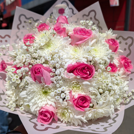 Dreamy bouquet with pink roses, white chrysanthemums, and baby’s breath in decorative wrap.