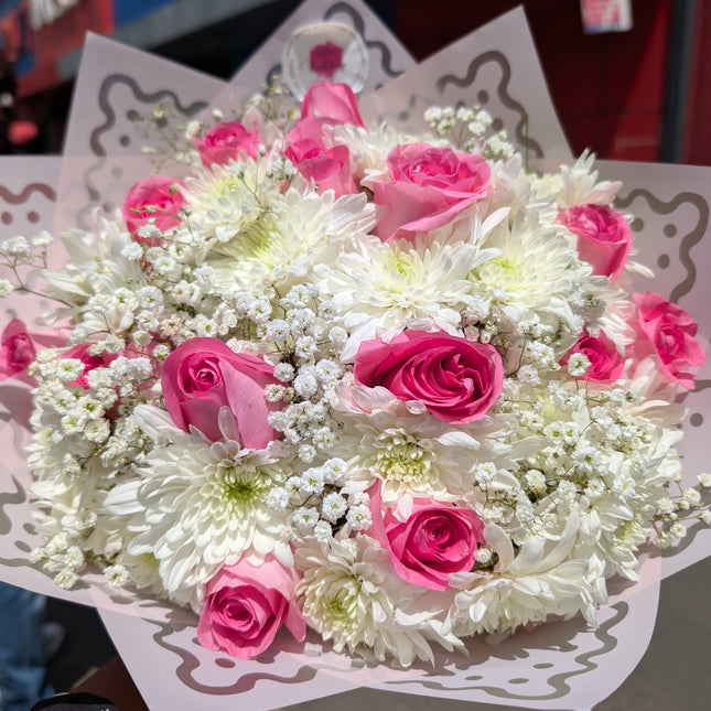 Dreamy bouquet with pink roses, white chrysanthemums, and baby’s breath in decorative wrap.