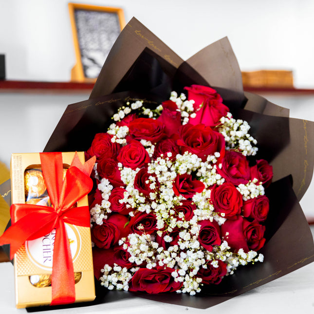 Linda bouquet with red roses, baby’s breath, black wrap, and gift chocolates with red ribbon.