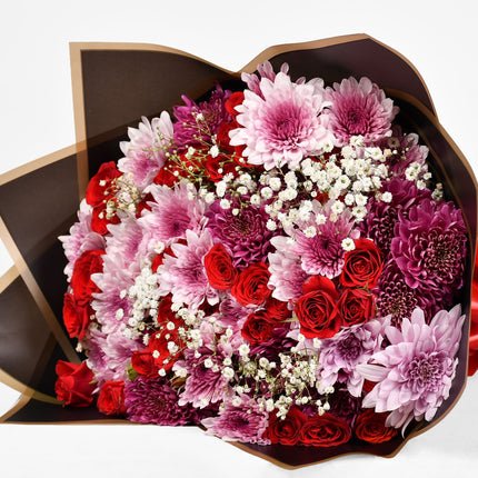 Spark bouquet with red roses, pink chrysanthemums, and baby’s breath in elegant wrap.