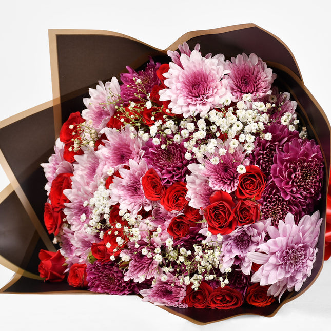 Spark bouquet with red roses, pink chrysanthemums, and baby’s breath in elegant wrap.